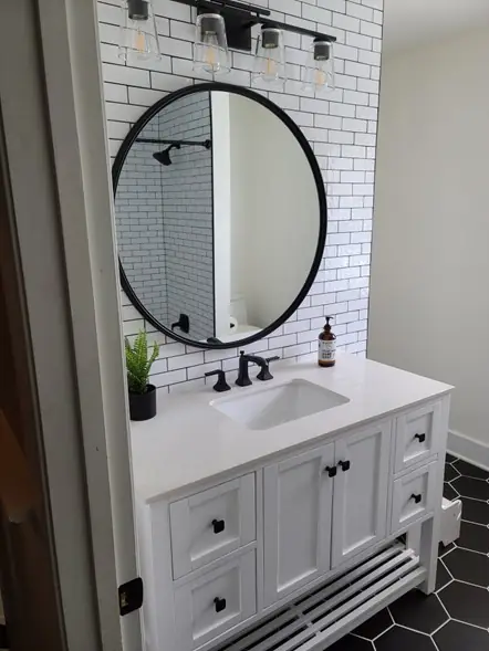 Completed white vanity, subway tile and round mirror in a finished bathroom