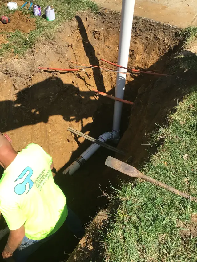 Chesapeake Plumbing technician in branded hi-vis shirt working in an open pipe trench