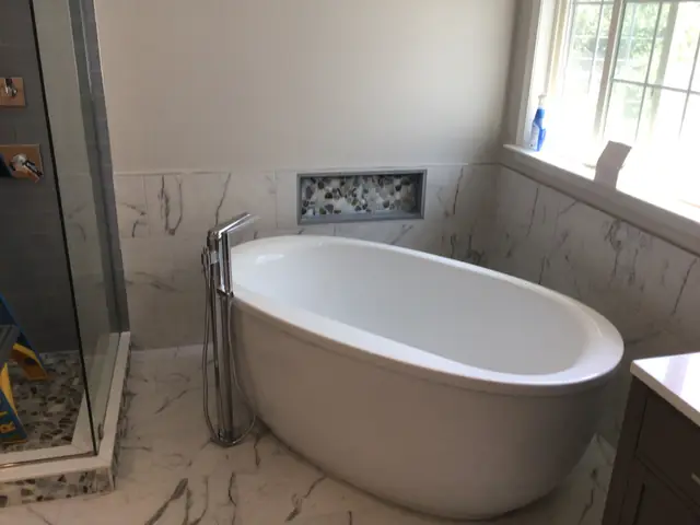 Freestanding tub and marble subway tile in a completed bathroom remodel