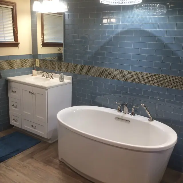 Blue subway tile bathroom remodel with a freestanding tub and new vanity
